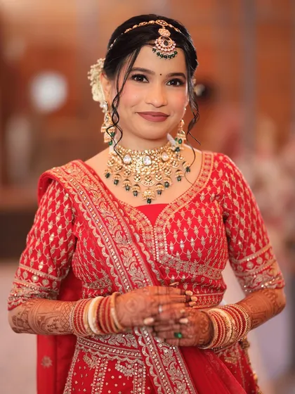 A beautiful portrait of the bride in her red lehenga. The soft, elegant updo and glowing makeup create a look that is the perfect blend of grace and glamour.