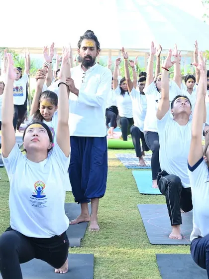 I am adjusting a student during our outdoor yoga session. Even in a large group, we provide individual attention.