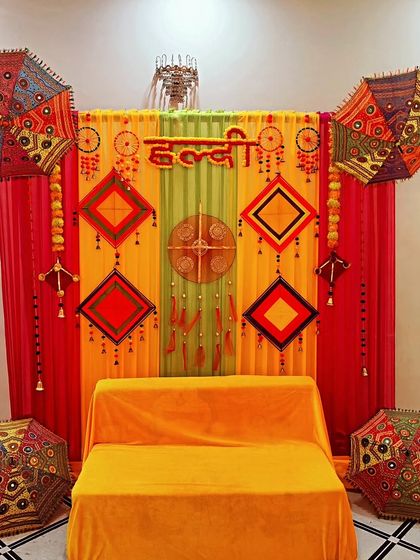 A simple and elegant Haldi backdrop with a comfortable seating arrangement, perfect for intimate home functions.