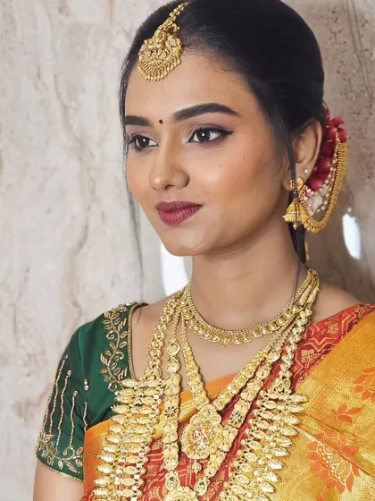 For Soundariya's muhurtham, we chose a classic look with winged eyeliner and a beautiful berry lip color. Her skin is glowing, and the makeup perfectly matches her green and orange Kanjivaram saree.