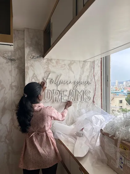 I am a hands-on architect, personally overseeing the installation of key design elements. Here I am on-site at a Vashi project, placing a "Follow your Dreams" neon sign, adding a final touch of inspiration to the space.