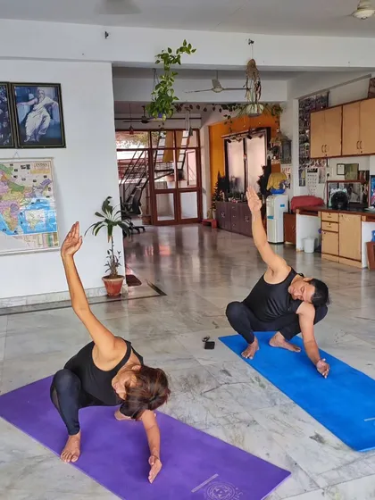 Two students practicing a twisting squat variation. My classes often include dynamic and creative flows that challenge the body and keep the practice interesting and engaging.