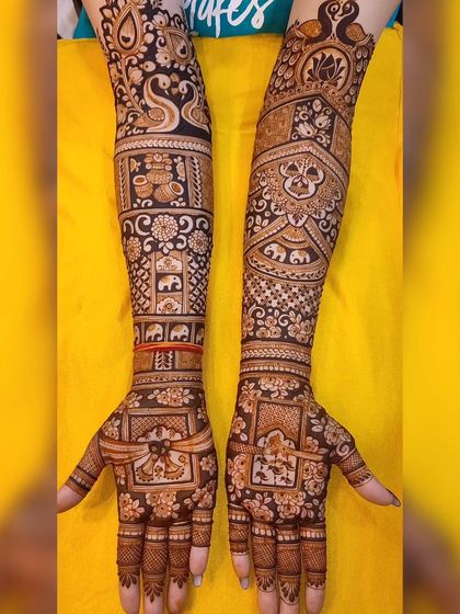 A full-arm bridal design against a bright yellow background. The artwork is packed with traditional motifs like peacocks, swans, and auspicious symbols.