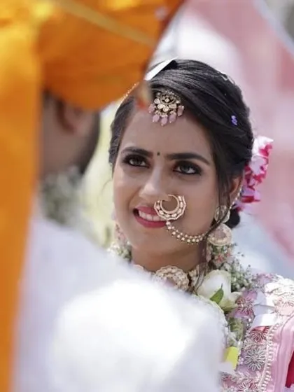 A candid wedding moment. The bride is wearing a delicate pastel choker and a matching maang tikka for a soft, romantic look.