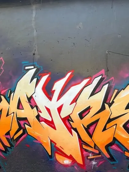 A clean and sharp graffiti piece in orange, white, and red. The lettering is a great example of wildstyle, where the letters are abstracted and interwoven in a complex format.