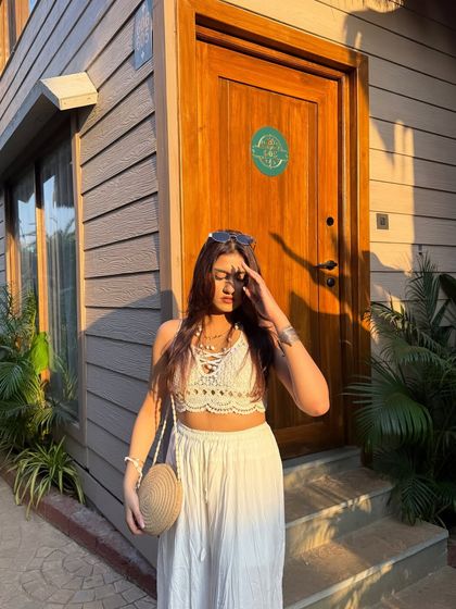 "Her aura so golden it's a statement." Enjoying the golden hour sunset at a beachside cafe in an all-white outfit.