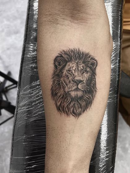 A small but powerful realistic lion head tattoo. Even in a smaller size, the detail in the mane and the lion's focused expression is captured perfectly.