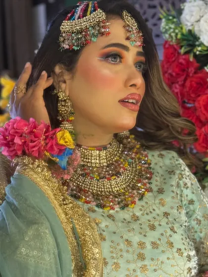 A close-up of the colorful Haldi makeup, paired with stunning multi-colored jewellery. The eye makeup uses shades of yellow, green, and orange.