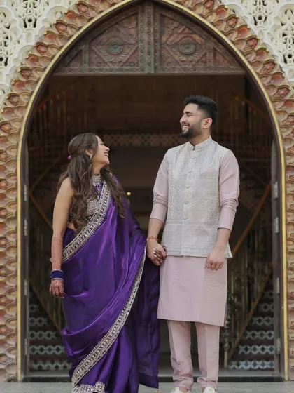 A classic couple portrait of Devanshi and Anshul. Standing in a beautifully carved archway, their shared look and hand-hold create a timeless and romantic image from their wedding day.