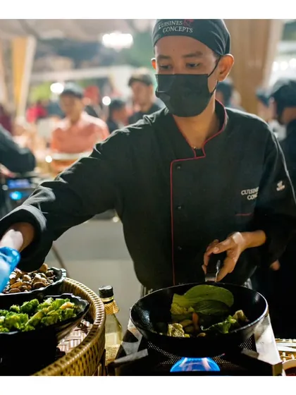 Another angle of our chef at the wok station, selecting fresh ingredients to toss into the pan. This emphasizes the made to order freshness that is a hallmark of our live cooking.