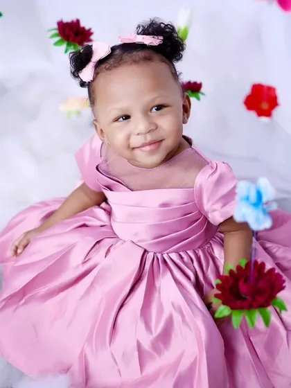A smiling portrait of the little girl holding flowers during her themed session.