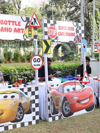 We set up several craft stations for the car-themed party, including bottle sand art and superhero cape making, all with custom 'Cars' movie branding.