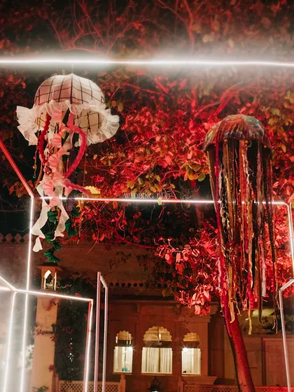 Whimsical, handmade jellyfish installations hang from a tree, framed by geometric neon lights. These pieces added a surreal, artistic touch to our London Underground themed party.