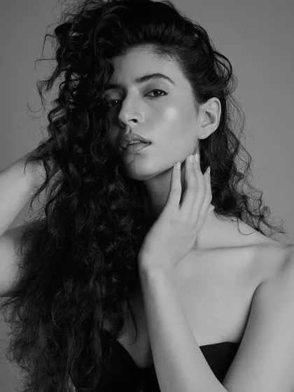 A soft and natural black and white portrait. The focus here is on the model's beautiful curly hair and her fresh, glowing skin. The makeup is minimal to let her natural texture and expression shine.