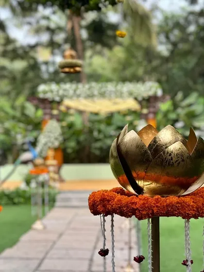 A detail shot of the wedding aisle, lined with golden lotus buds on stands, leading to a beautiful mandap in the background. These details add a touch of divinity to the path.