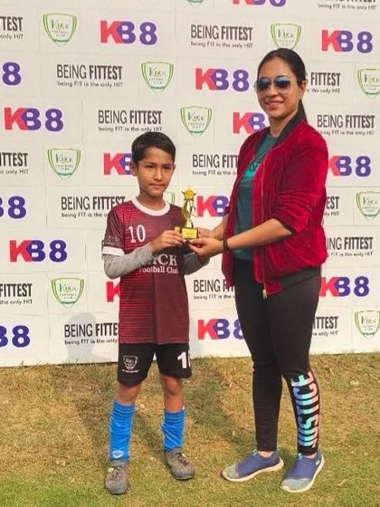 A Kick FC player receives his "Player of the Match" trophy for his standout performance.