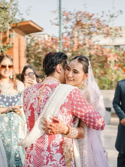 A heartfelt hug between the bride and groom, surrounded by their cheering friends and family. This is a moment of pure love and support, beautifully captured.