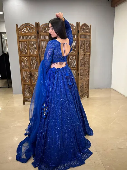 A back view showcasing the open-back design and the full, flowing skirt of the blue lehenga.