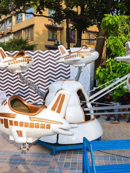 This space-themed airplane carousel features sleek white and gold shuttles, perfect for an astronaut or outer space adventure party.