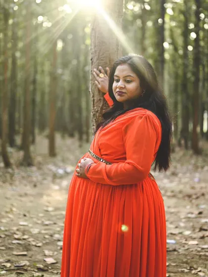 For this maternity session, we went to a beautiful forest trail to capture the perfect shot. The sunlight filtering through the trees created this stunning natural glow on the mother-to-be in her vibrant red dress, making for a truly magical portrait.