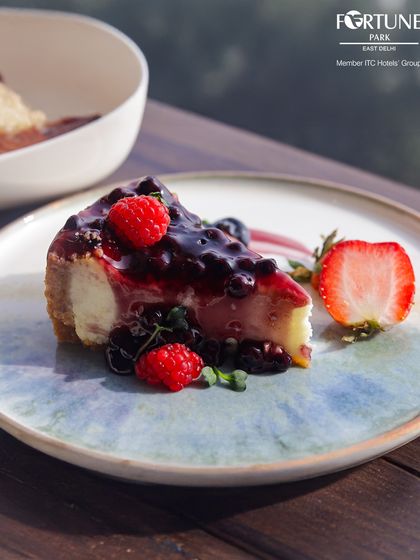 A slice of our decadent blueberry cheesecake, topped with a rich berry compote and fresh strawberries.
