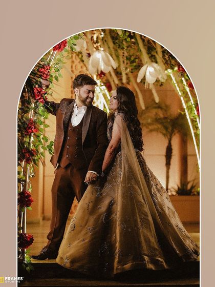 A groom and bride at their reception. The groom is wearing a custom dark brown three-piece suit that perfectly complements the warm tones of the decor and his bride's outfit.