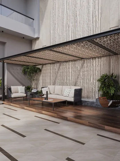 This outdoor seating area is sheltered by a pergola with an intricate laser-cut pattern, which casts beautiful shadows throughout the day. A textured stone wall serves as a dramatic backdrop, blending art and architecture.