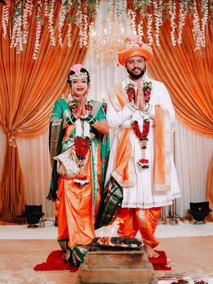The bride and groom stand together with hands joined in 'namaste' before the sacred fire. This portrait captures their reverence and shared commitment during the wedding pheras.