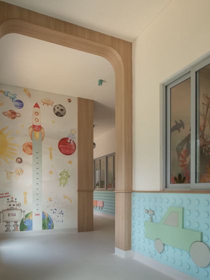 A view down a nursery corridor, where a space-themed mural with a rocket height chart makes tracking growth an exciting event. The wooden archways add a soft, architectural detail to the space.