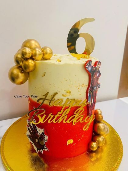 An Iron Man cake fit for a superhero's 6th birthday. The bold red and gold design, complete with a shiny number topper and golden spheres, makes for an action-packed celebration.