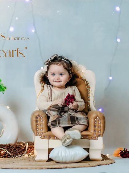 Children see magic because they look for it. A sweet girl in a plaid skirt sits in a miniature armchair in our cozy studio.