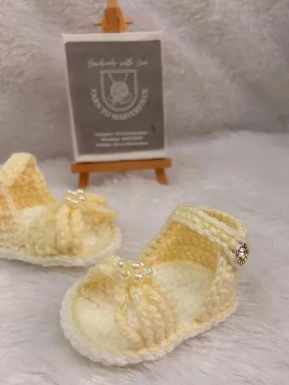 My baby girl sandals in a soft yellow, featuring a delicate bow with pearl accents and a secure ankle strap.