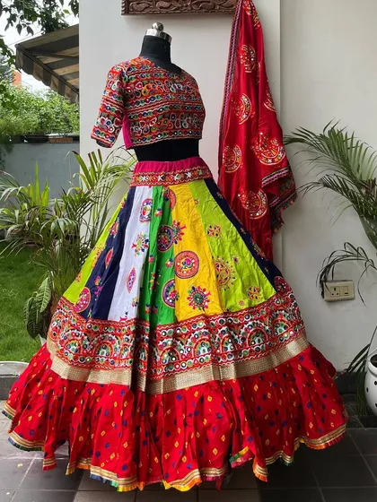 This multi-colored lehenga has it all: a vibrant panelled skirt, a ruffled red border, and a beautifully embroidered blouse. A true showstopper.