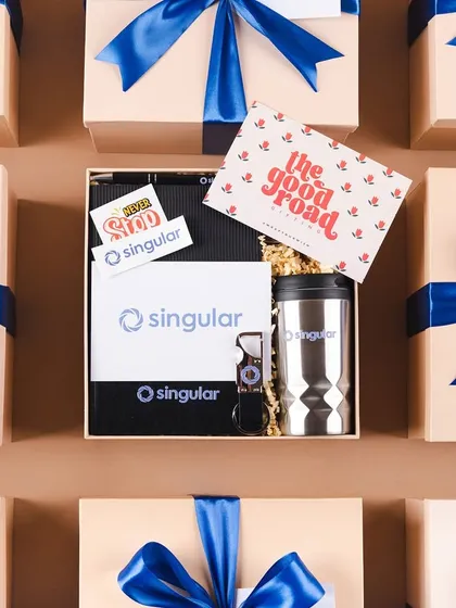 We love seeing our workshop filled with beautifully branded boxes ready for dispatch. This flat lay shows a batch of custom welcome kits for our client Singular, each packed with care and tied with their signature blue ribbon, ensuring a consistent and professional brand experience.