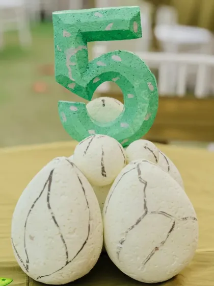Themed table decor, like this number '5' centerpiece with dinosaur eggs, adds a perfect finishing touch to the party.
