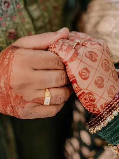 A close-up of the couple's hands, displaying their engagement rings, a simple and powerful symbol of their commitment.