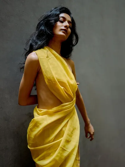 A minimalist portrait from a test shoot, featuring a model draped in yellow fabric. The pose is elegant and sculptural, emphasizing the human form.
