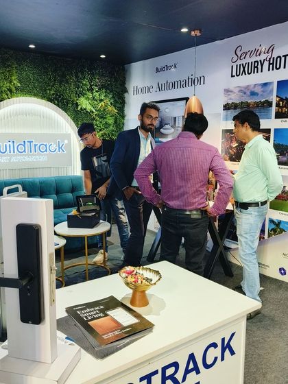 Our team engaging with visitors at our NEXKNOS 2024 booth, which featured a lush green wall and a comfortable seating area.