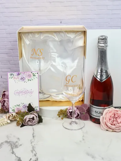 A celebration in a box. This hamper features two personalized wine glasses and a bottle of sparkling wine, making it a perfect gift for an engagement, anniversary, or any special occasion.