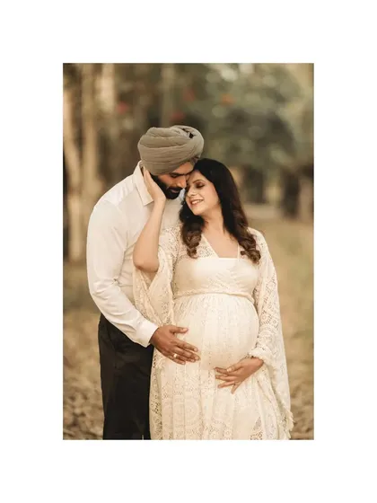 A tender embrace in the woods. The father-to-be gently caresses his partner's face, a gesture of love and care, beautifully captured in this outdoor portrait.