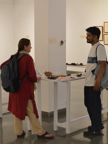 Artist Mohit Mahato engaging with a visitor, explaining the concepts behind his collection of found objects and drawings.