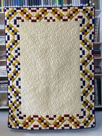 A Jacob's Ladder quilt made with elegant silk fabric, featuring a cream center and a colorful border.