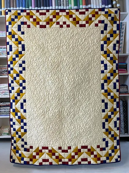 A Jacob's Ladder quilt made with elegant silk fabric, featuring a cream center and a colorful border.
