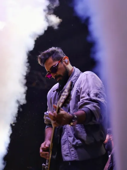I work with the elements of the stage, using smoke and dramatic lighting to frame the musician. This shot captures the atmosphere of a live show, where the music itself feels visible.