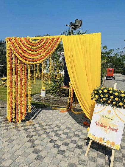 A simple yet beautiful entrance for a Haldi ceremony, welcoming guests to "Yellow Land." We used traditional genda phool garlands and yellow drapes to create a warm and inviting entryway.