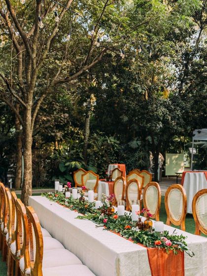 An elegant long-table dining setup for an intimate wedding cocktail party. The floral runner and candles create a warm and inviting atmosphere for guests.