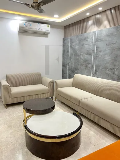 A complete living room set featuring a beige channel-tufted sofa and loveseat, paired with bold orange high-back chairs. The nesting coffee tables with marble tops complete this vibrant and modern look.