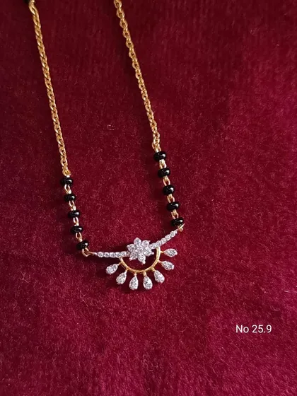 A beautiful mangalsutra with a semi-circular pendant adorned with American diamonds. The design is modern and stylish, perfect for the contemporary woman.