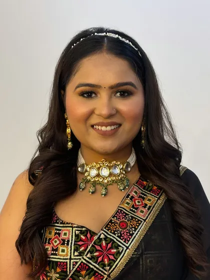 A smiling portrait of the client, showing how the makeup brightens her face and complements her traditional yet modern outfit.