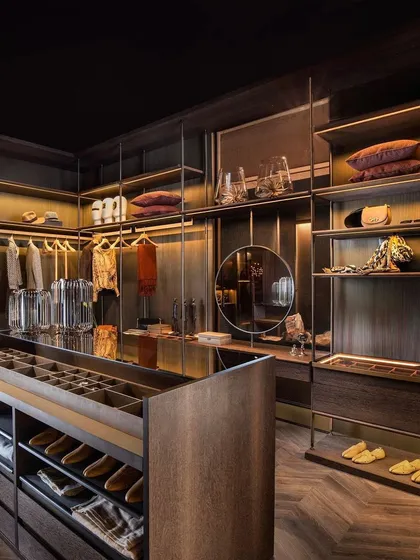 This is our APERTO open wardrobe system, designed to make your room feel more spacious. By replacing bulky side panels with sleek vertical metal supports, the structure feels light and airy, offering a modern, customizable storage solution with shelves and drawers in rich succupira veneer.